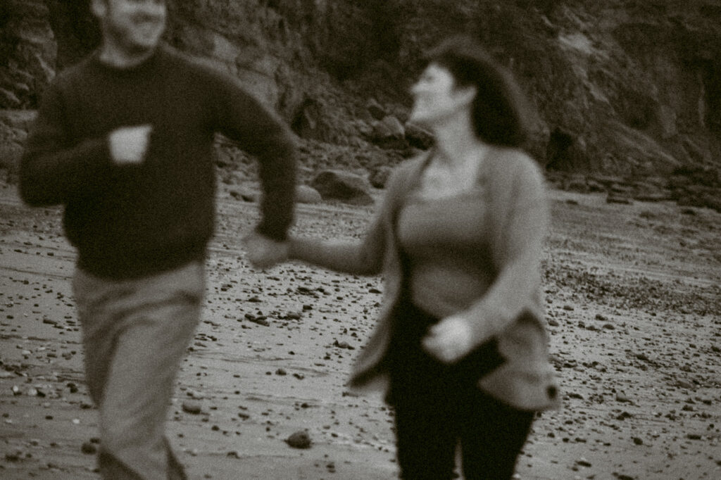 An out-of-focus black and white image of a man and woman running towards the camera.