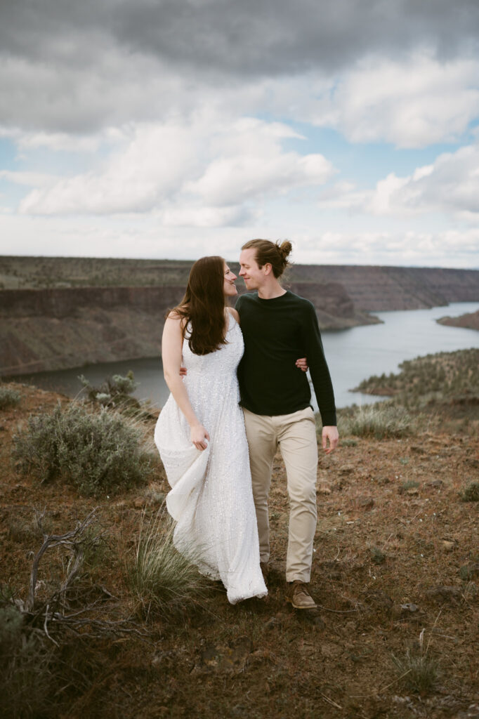 A man and woman walk arm-in-arm towards the camera, looking at one another and smiling.