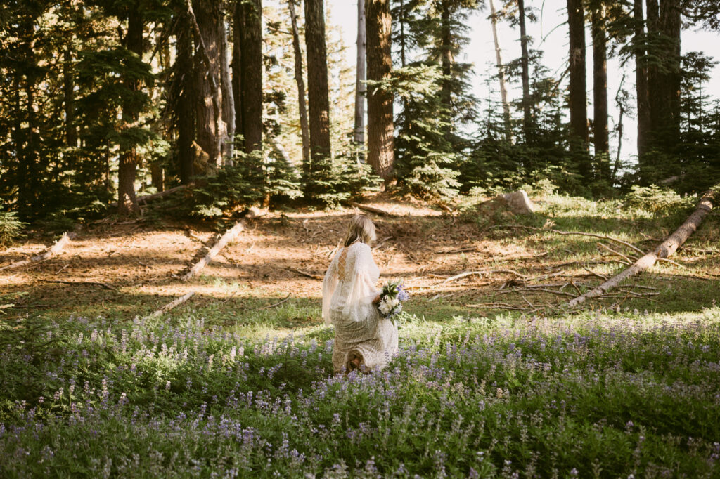 An Oregon bride picks her way through a field of wildflowers on her wedding day.