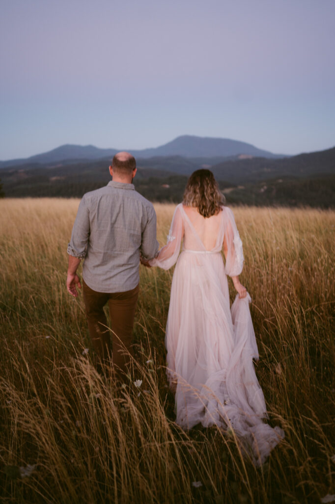 A married couple walk hand-in-hand along a footpath at Fitton Green in Corvallis, Oregon at sunrise. Mary's Peak can be seen in the background.