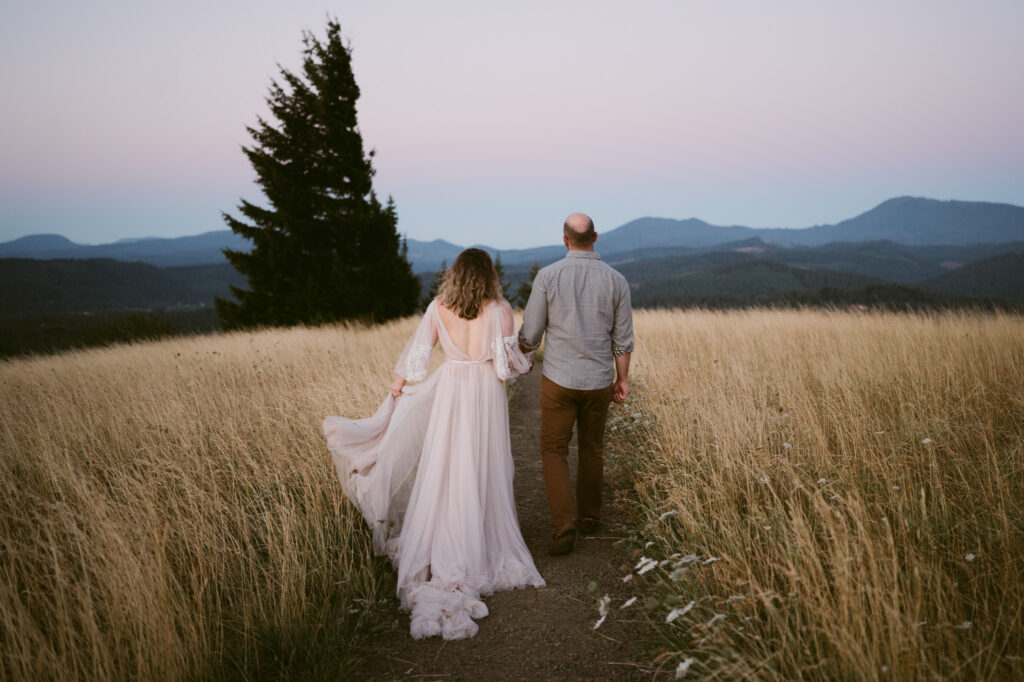 An adult couple walk hand in hand down a footpath during sunrise at Fitton Green in Corvallis, Oregon.