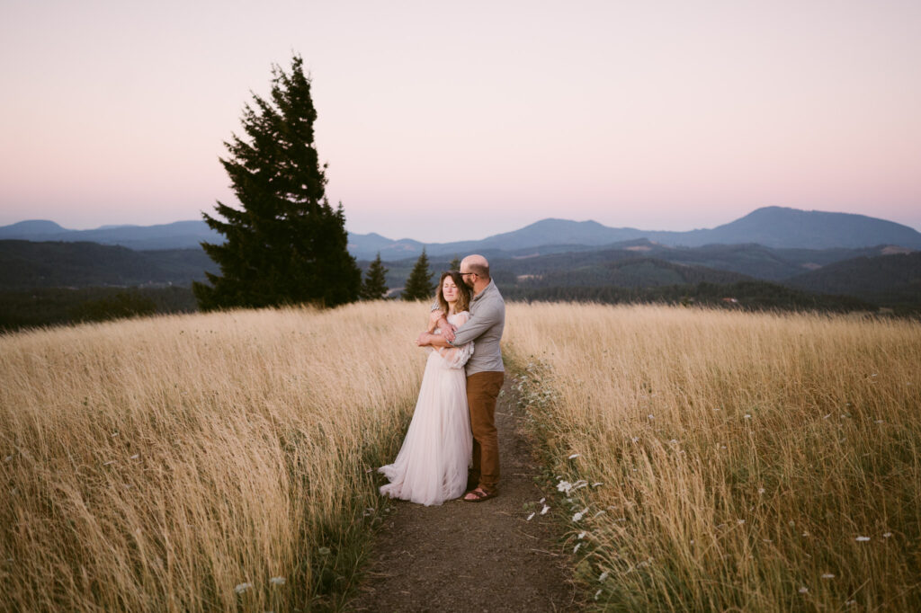 Oregon's coastal range can clearly be seen behind a man and woman standing at Fitton Green during sunrise.