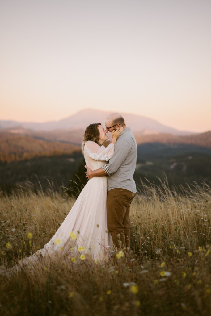 Mary's Peak catches the first rays of sun while a couple stands kissing in front of it during their engagement session at Fitton Green.