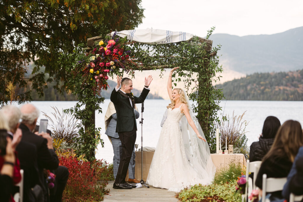 Bride and groom cheer as they're pronounced husband and wife during their Whiteface Club & Resort wedding.