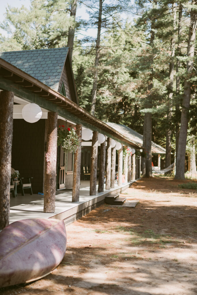 Celebratory white paper lanterns line the back porch of an Adirondack cabin, hanging in anticipation of a wedding.