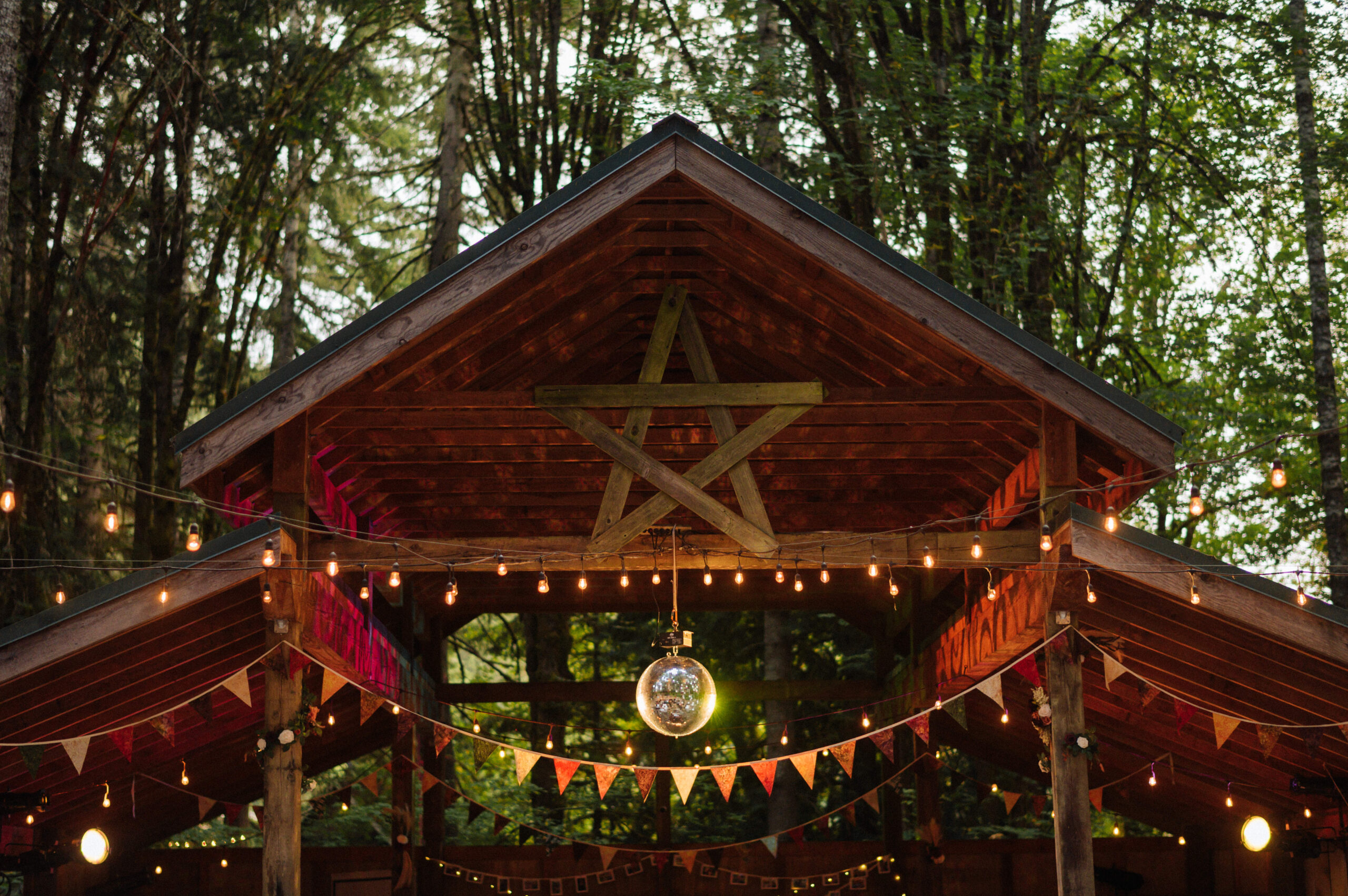 The outdoor pavilion at Camp Cedar Ridge in Vernonia, Oregon is festively decorated with edison bulbs, garlands, and a disco ball.