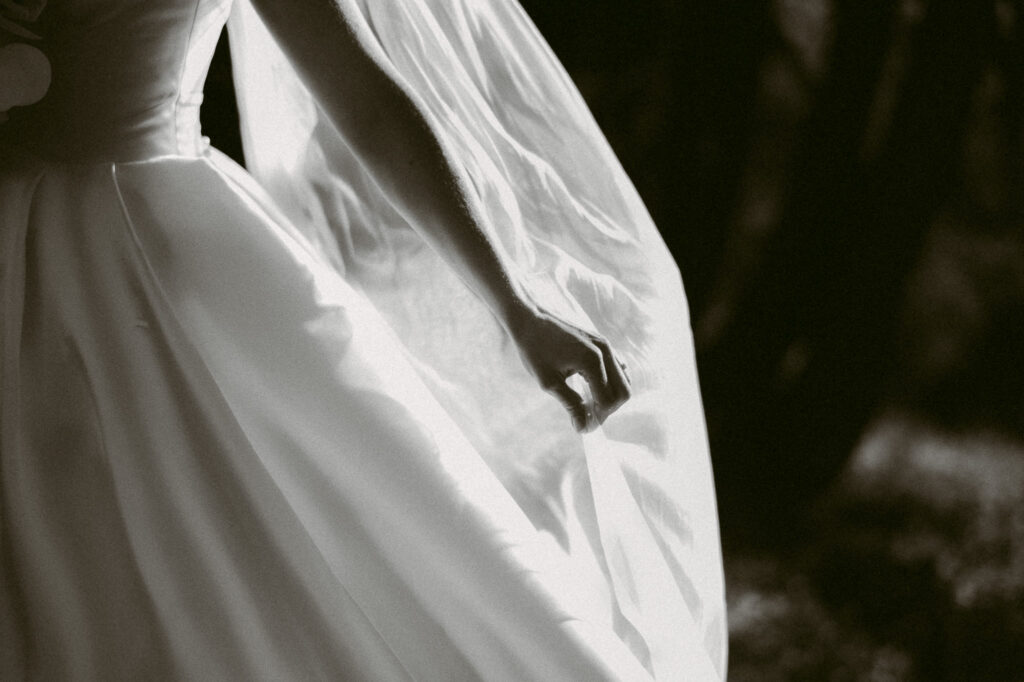 Black and white detail of bride’s hand gently holding her veil during a mountain elopement along the Pacific Crest Trail.