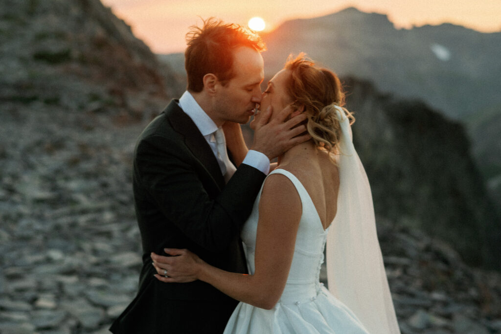 Close-up of a romantic kiss between the newlyweds as the sun sets behind them in the Goat Rocks Wilderness.