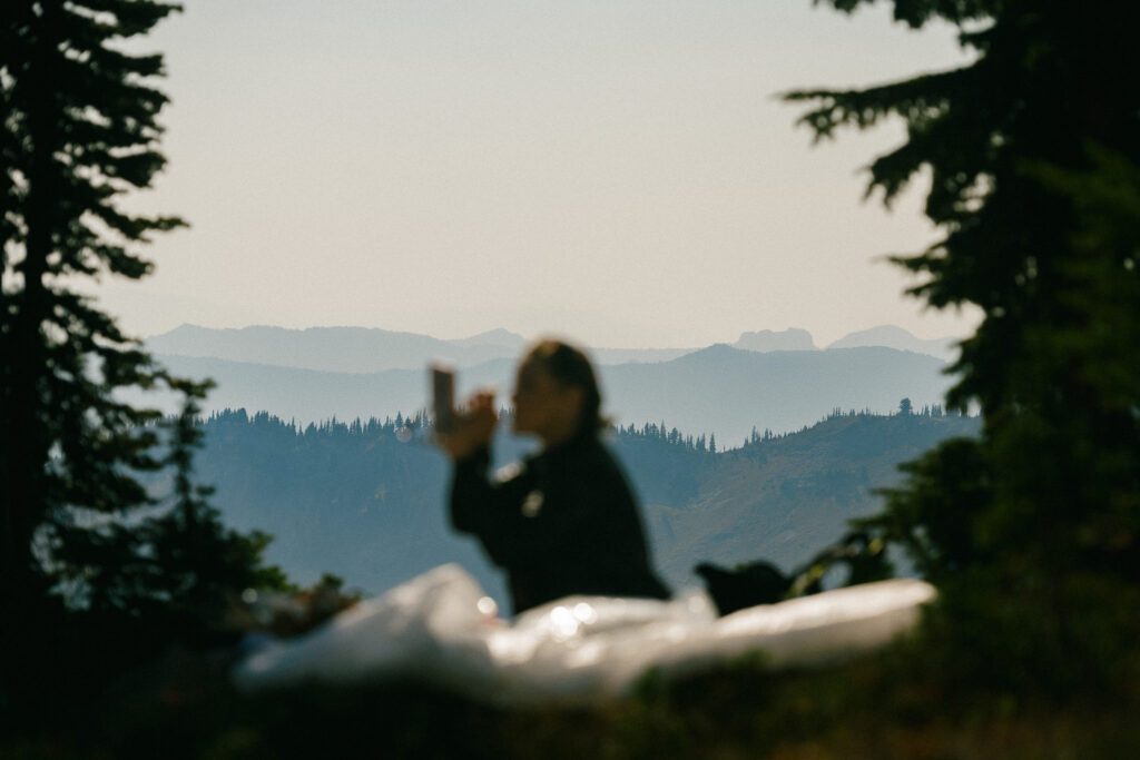 Bride silhouetted against the layered mountain ridges of Goat Rocks Wilderness while reading vows during a peaceful PCT elopement moment.