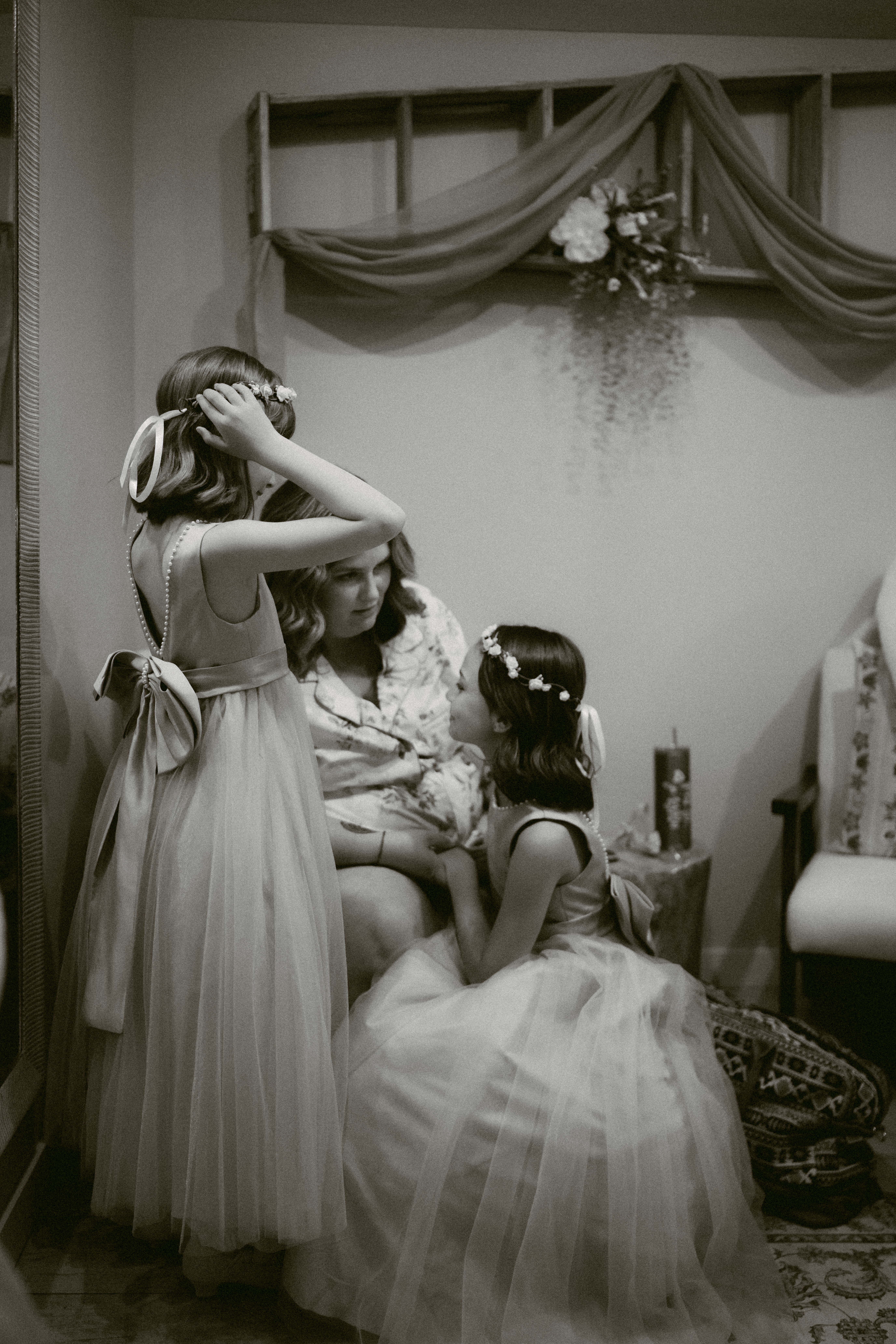 Two flower girls in tulle dresses share a sweet moment with a bridesmaid in the cozy getting-ready suite at Applegate Ranch in Grants Pass.