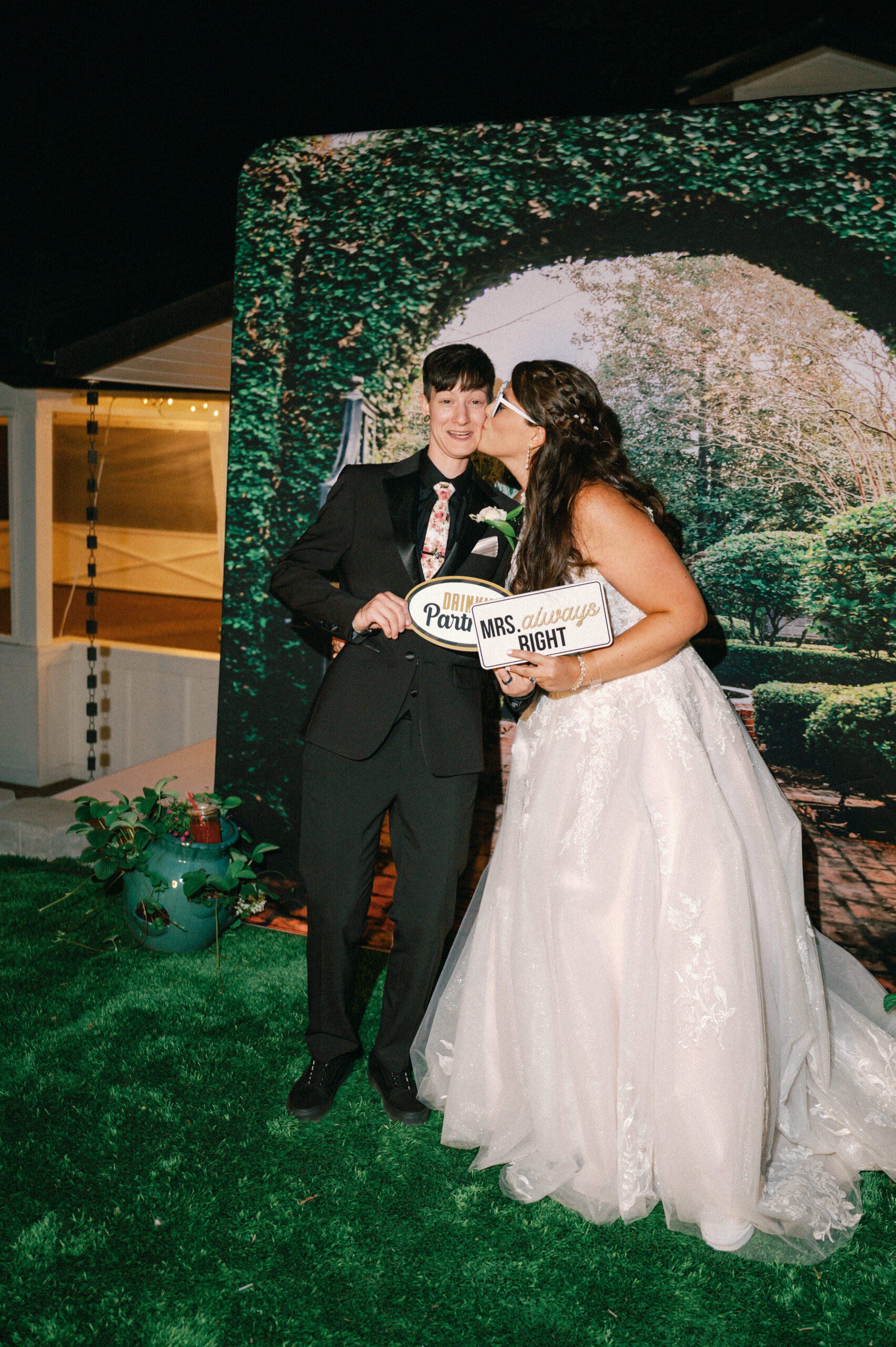 A playful photo booth moment with the bride kissing her partner’s cheek while holding a sign reading “Mrs. always RIGHT.”