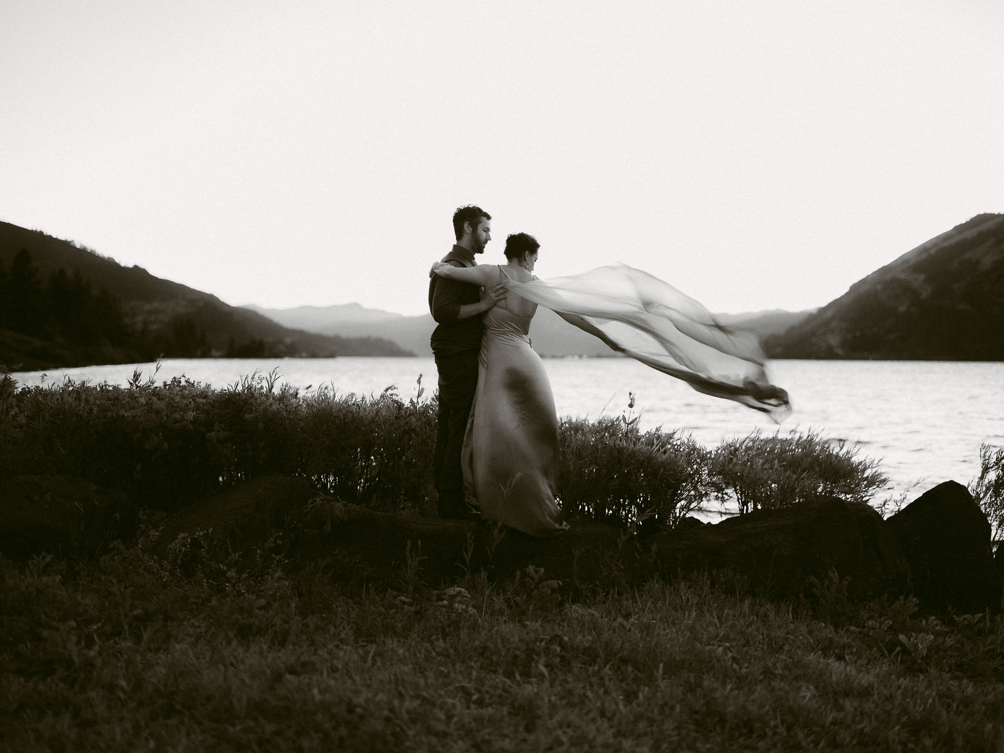 The bride gazes over her shoulder toward the Columbia River at sunset, her veil softly catching the breeze.