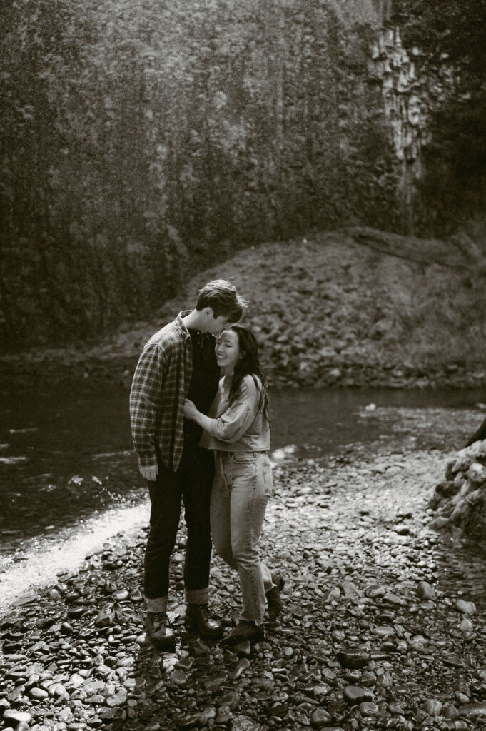 A black and white image of a couple playfully embracing during their Abiqua Falls engagement session.