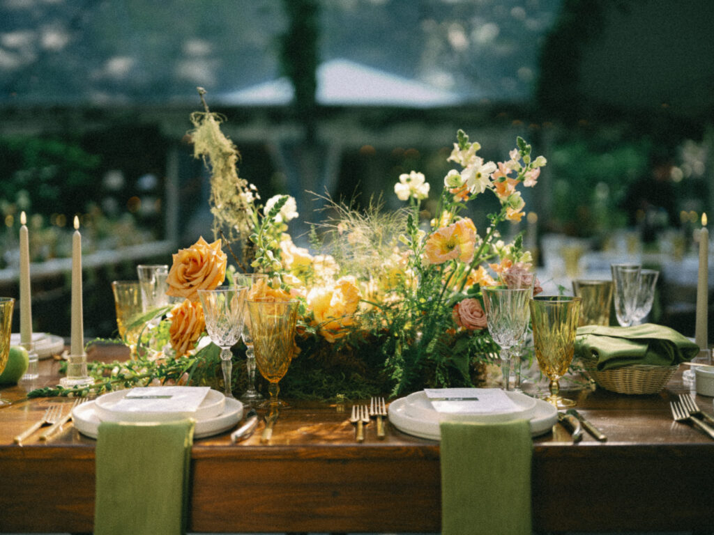 Reception table set with floral centerpieces, candles, and glassware during a joyful summer wedding at the Griffin House.