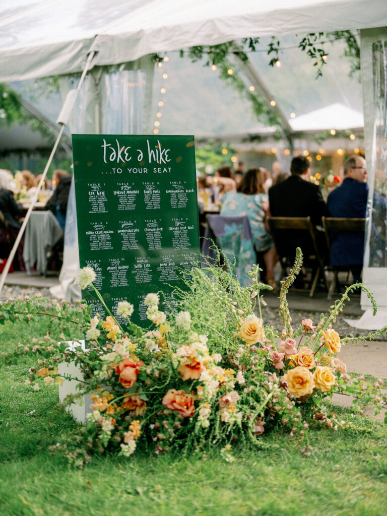 Escort display reading “Take a hike to your seat,” surrounded by lush florals and greenery at the Griffin House wedding reception.
