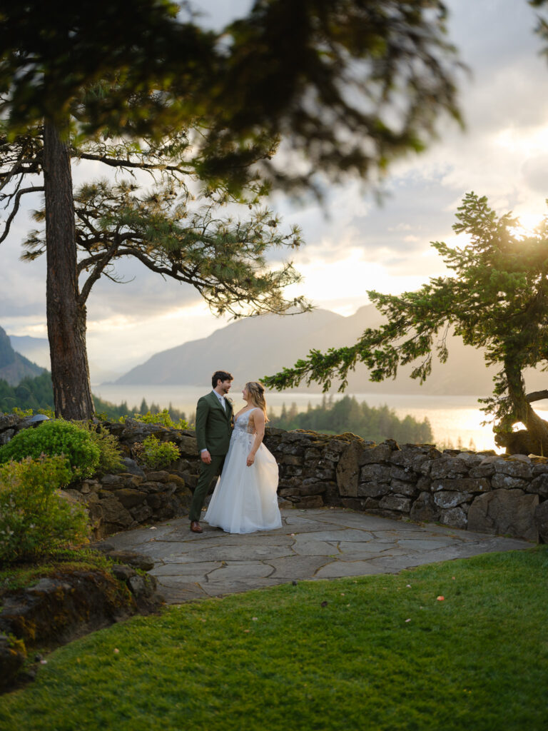 The newlyweds standing arm in arm at sunset, overlooking the Columbia River Gorge from the Griffin House property.