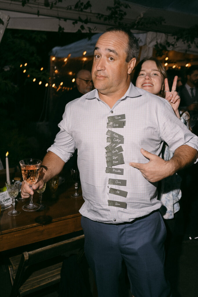 A guest playfully posing on the dance floor wearing name tags during the Griffin House wedding reception.