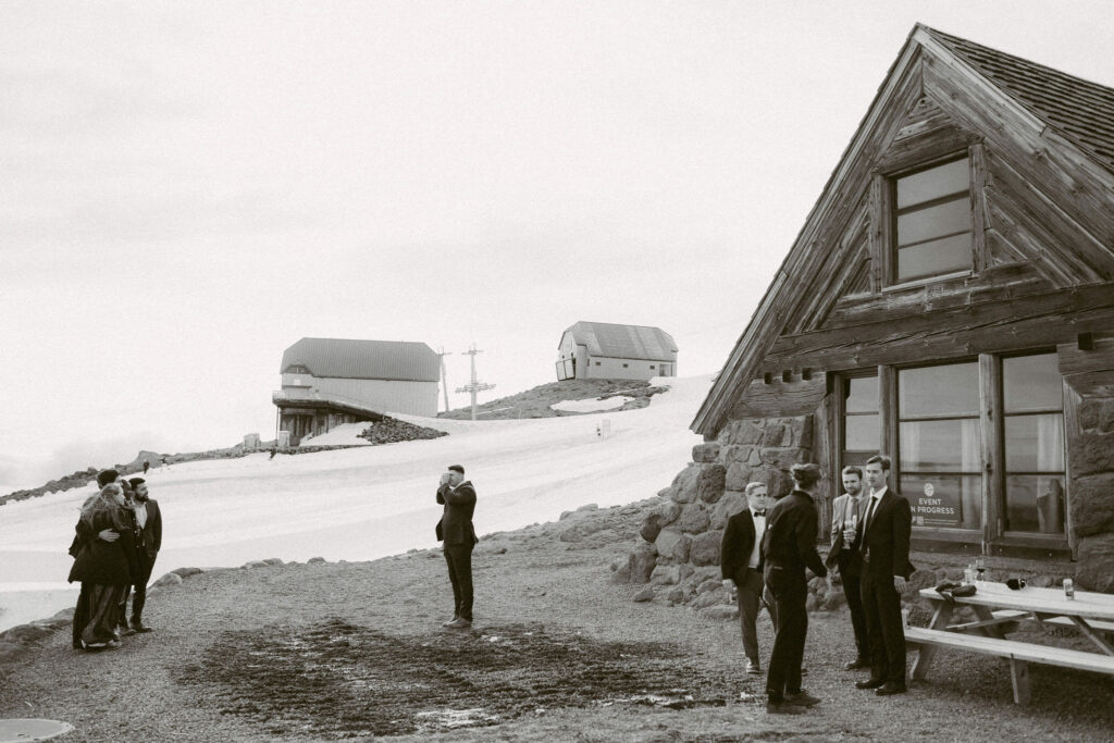 Wedding guests gather outside Silcox Hut, taking photos and chatting near the snowy ski lifts on Mount Hood.