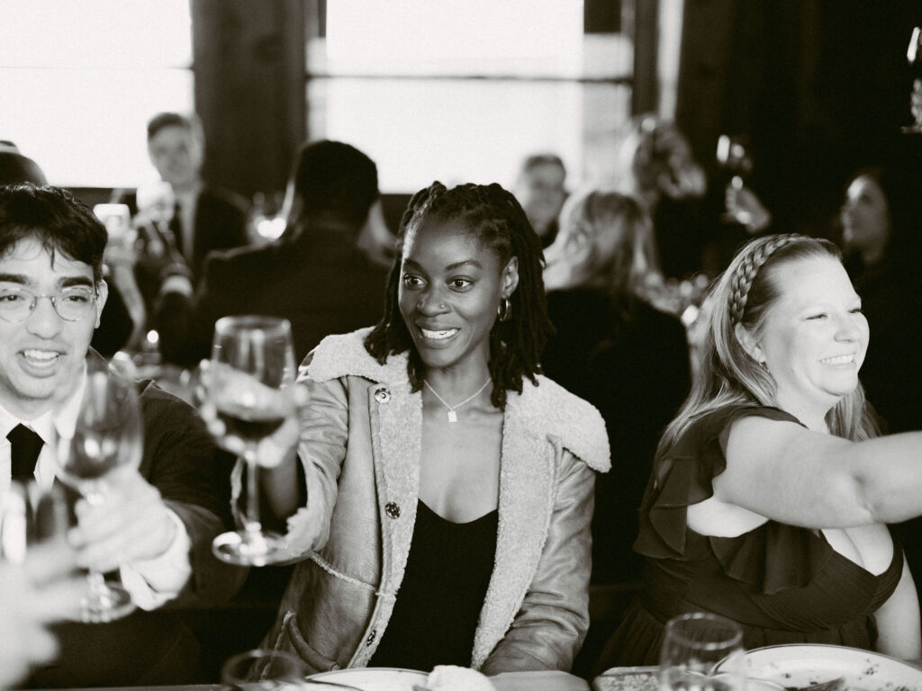 Wedding guests raise their glasses in a joyful toast inside the warm, wood-lined reception space at Silcox Hut.