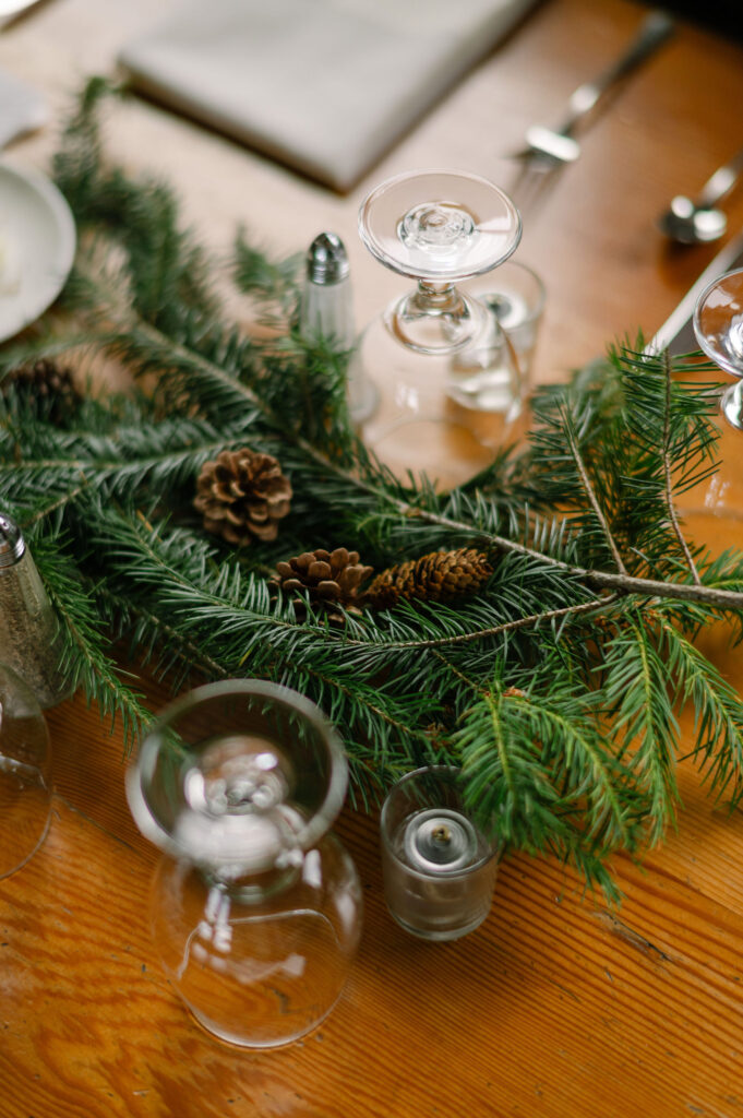A close-up of evergreen branches and pinecones arranged as natural table décor for a cozy Silcox Hut wedding reception.