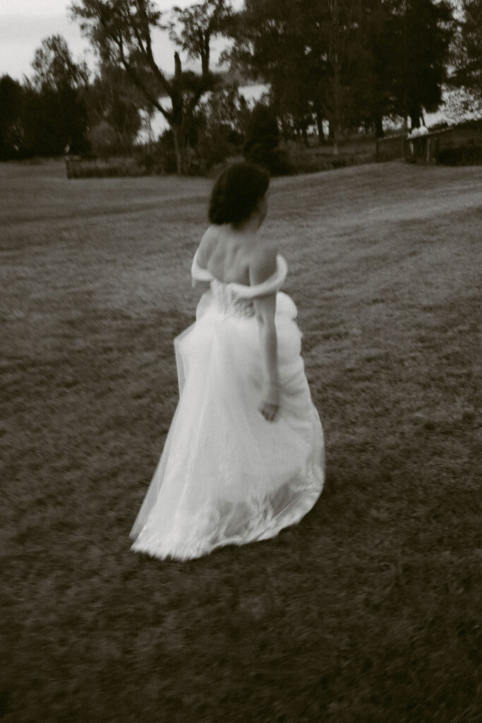 Motion-blurred photo of the bride walking across the lawn at the White House on the Lake, her dress flowing behind her.