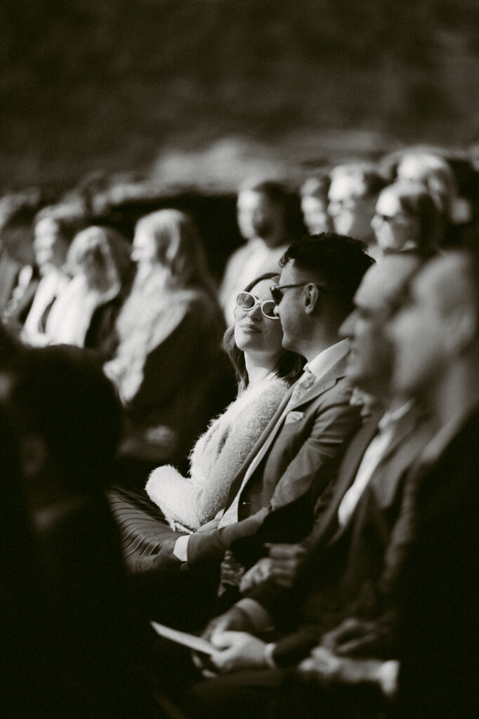 Black and white photo of wedding guests sharing a quiet, emotional moment during the ceremony at the Griffin House.