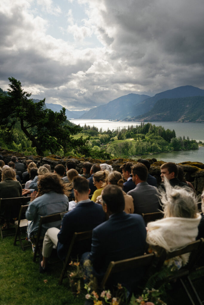Guests seated for a ceremony at the Griffin House, overlooking the Columbia River Gorge under dramatic summer skies.