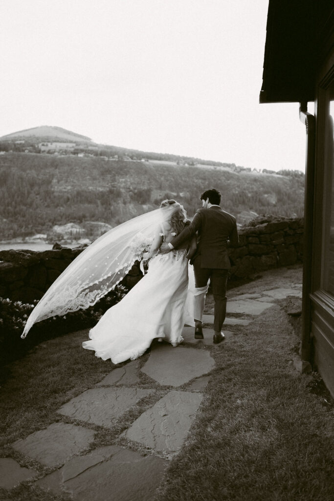 Black and white image of the couple walking together after the ceremony at the Griffin House, the bride’s veil flowing in the wind.