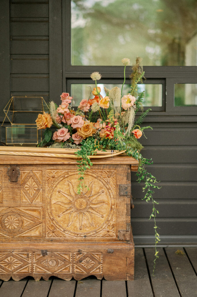 Floral arrangement displayed on a vintage wooden chest during a summer wedding at the Griffin House.