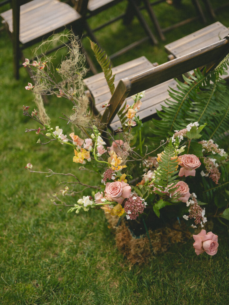 Floral arrangements attached to ceremony chairs at the Griffin House, featuring soft pink and peach blooms with greenery.