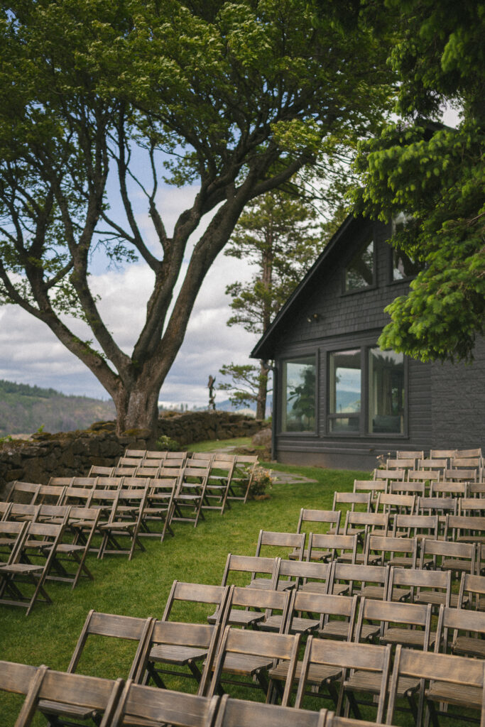 Rows of wooden chairs set for an outdoor ceremony at the Griffin House, framed by trees and Columbia River Gorge views.