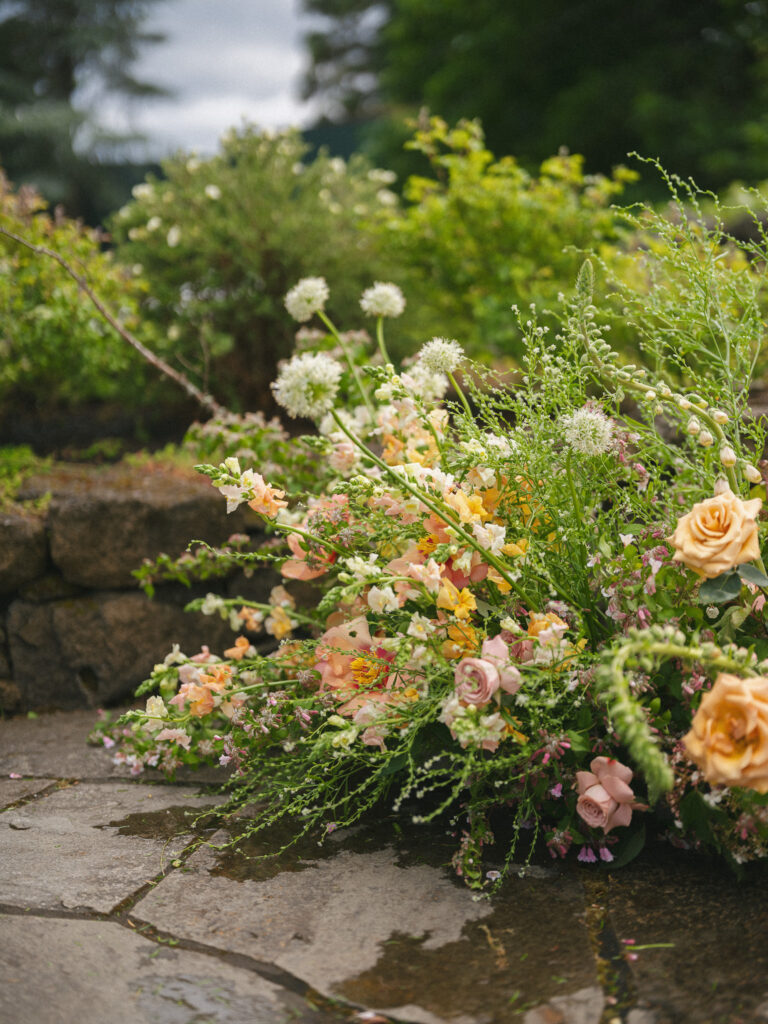 Lush summer florals arranged along a stone walkway at the Griffin House, blending garden roses, wildflowers, and greenery.