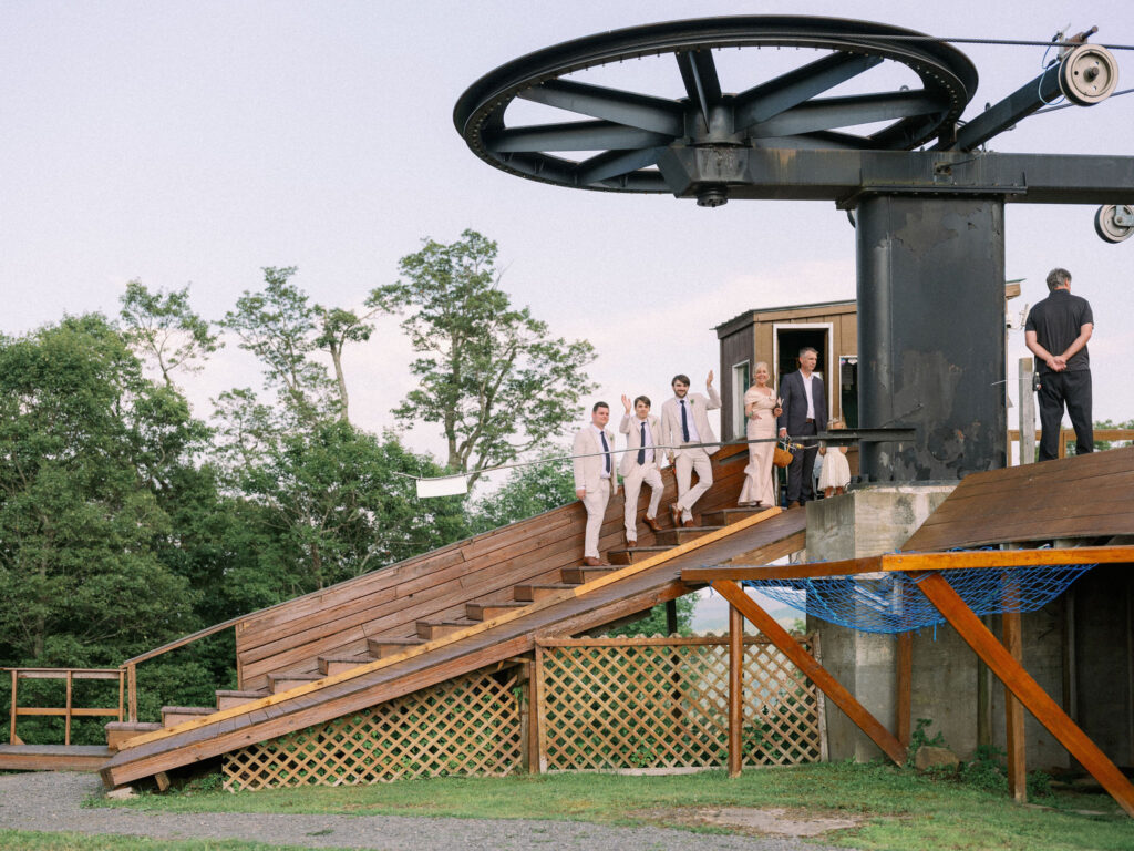 The groomsmen, along with family members, walk down the wooden stairs beside the Oak Mountain ski lift after the ceremony.