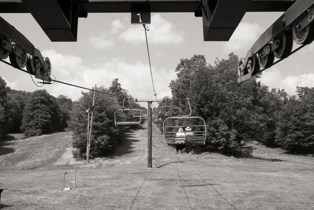 Guests ride the chairlift up Oak Mountain for the wedding ceremony, captured in a timeless black-and-white image with trees lining the slope.