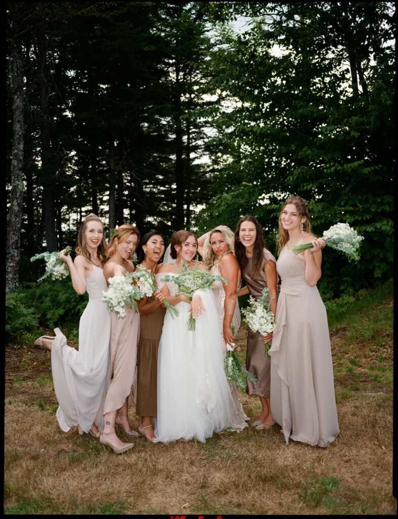 Film photograph of the bride and bridesmaids posing together near the wooded edge of Oak Mountain, bouquets in hand and sunlight filtering through the trees.