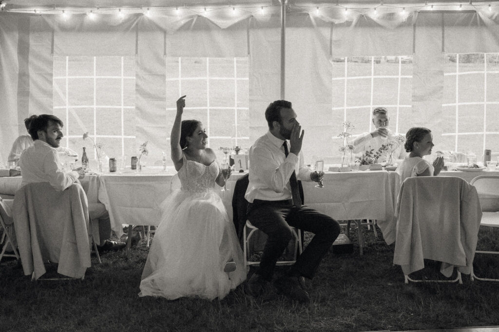 Bride and groom cheering under the reception tent during their Speculator, NY wedding celebration.