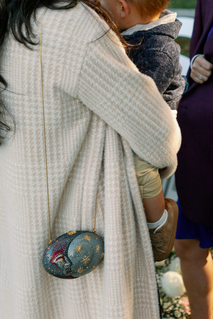 Close-up detail of a wedding guest holding a young child during an outdoor fall ceremony in Lake Placid.