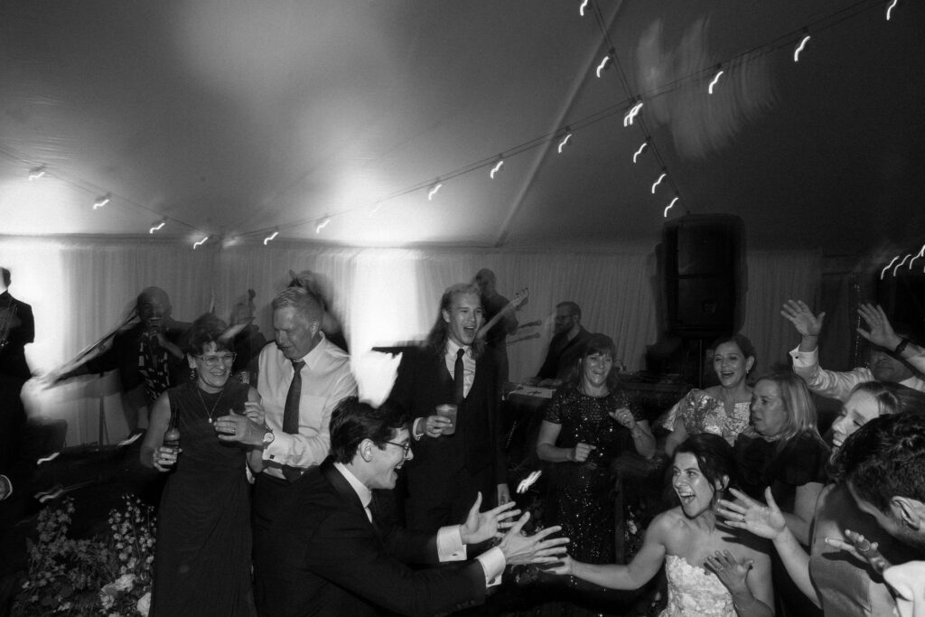 Guests dance energetically under string lights during a lively wedding reception in Lake Placid, New York.