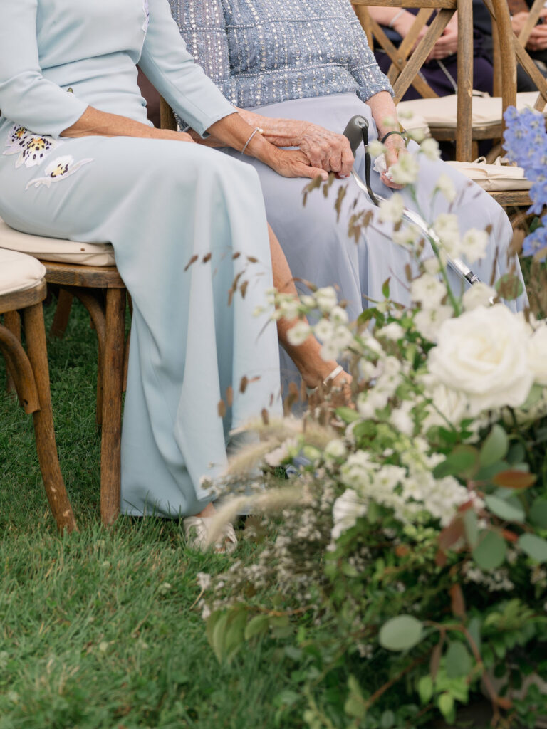 Guests holding hands with cane during Lake Placid private estate wedding ceremony with floral aisle details