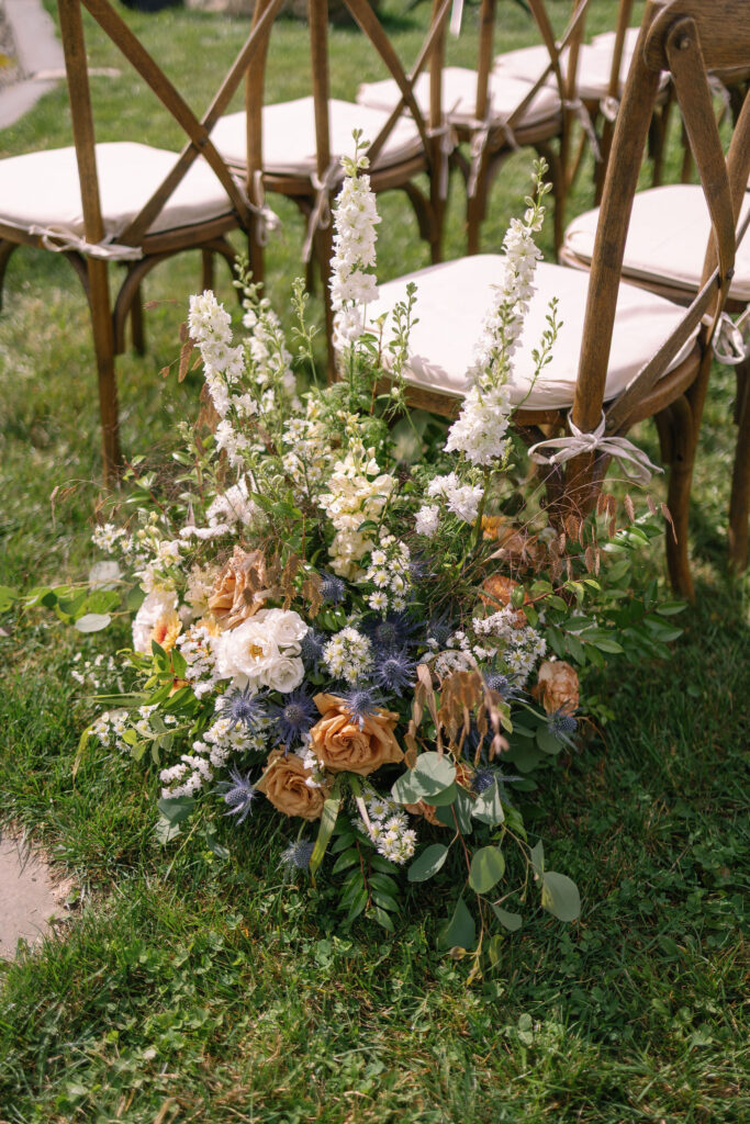 Ceremony aisle floral installation with garden-style arrangements at a Lake Placid private estate wedding
