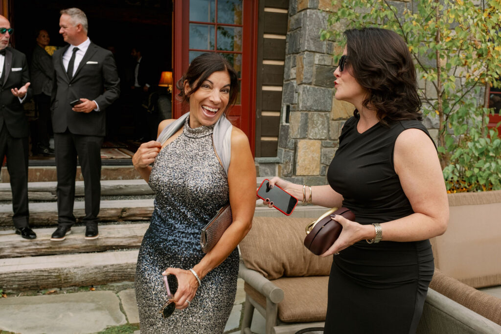 Wedding guests arriving and chatting outside rustic cabin at Lake Placid private estate wedding