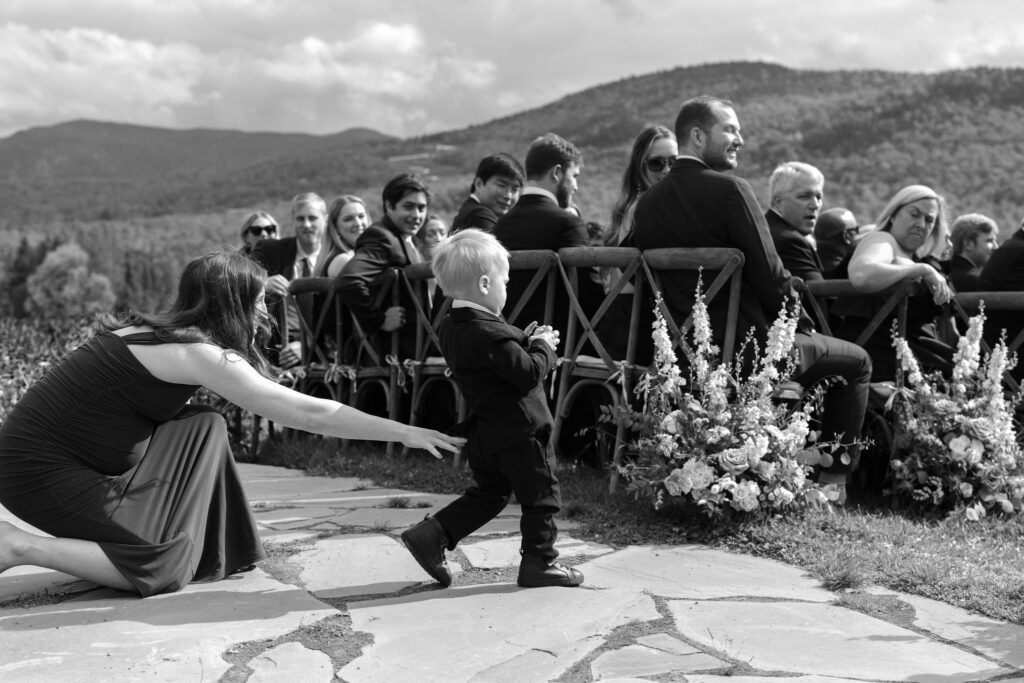 Guest reaching for ring bearer during outdoor Lake Placid private estate wedding ceremony