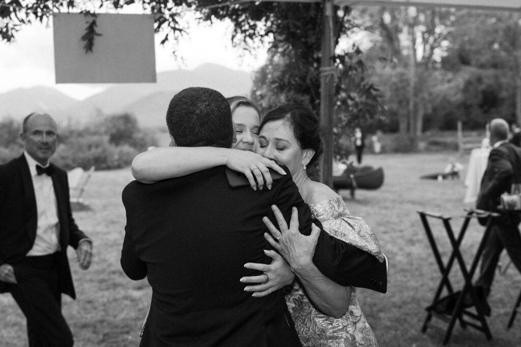 Family members share an emotional group hug during cocktail hour at a Lake Placid, New York wedding.