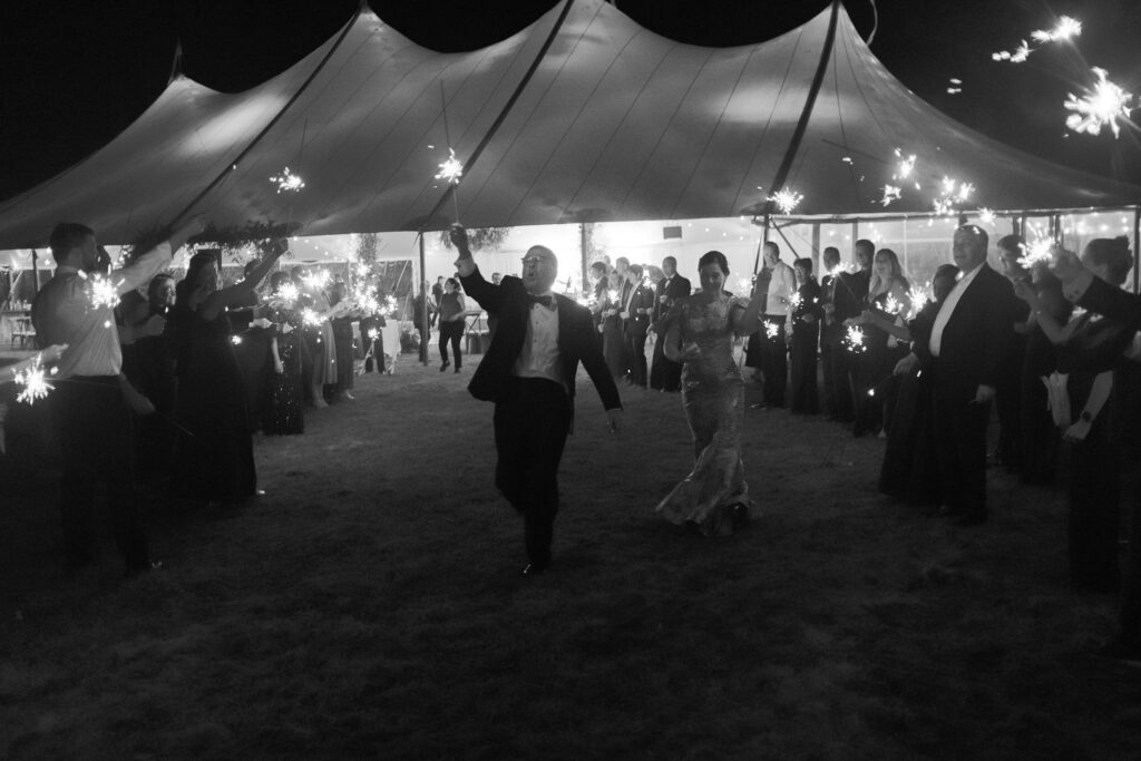 Wedding guests form a glowing sparkler tunnel outside a tented reception in Lake Placid, New York.