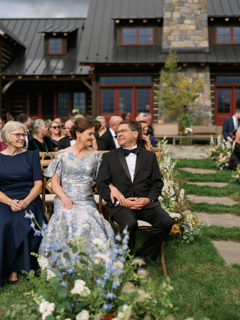 Parents of groom seated during Lake Placid private estate wedding ceremony with floral aisle