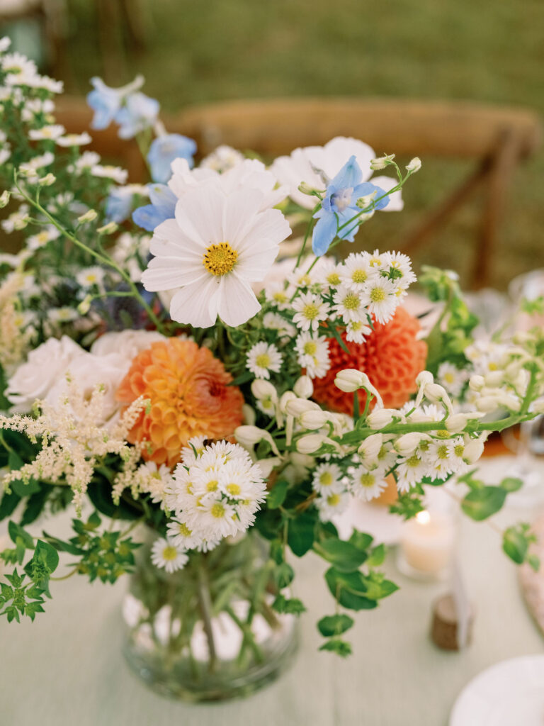 Garden-style wedding centerpiece with cosmos, dahlias, and wildflowers in soft pastel tones on a reception table in Lake Placid.