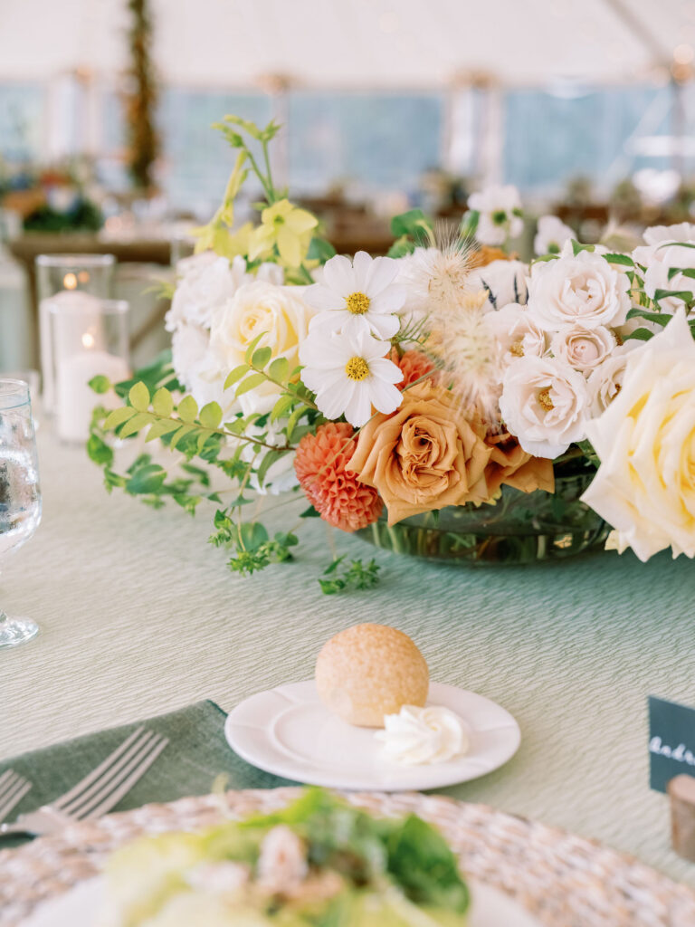 Reception table setting with floral centerpiece, candlelight, and plated bread at a Lake Placid, New York wedding.