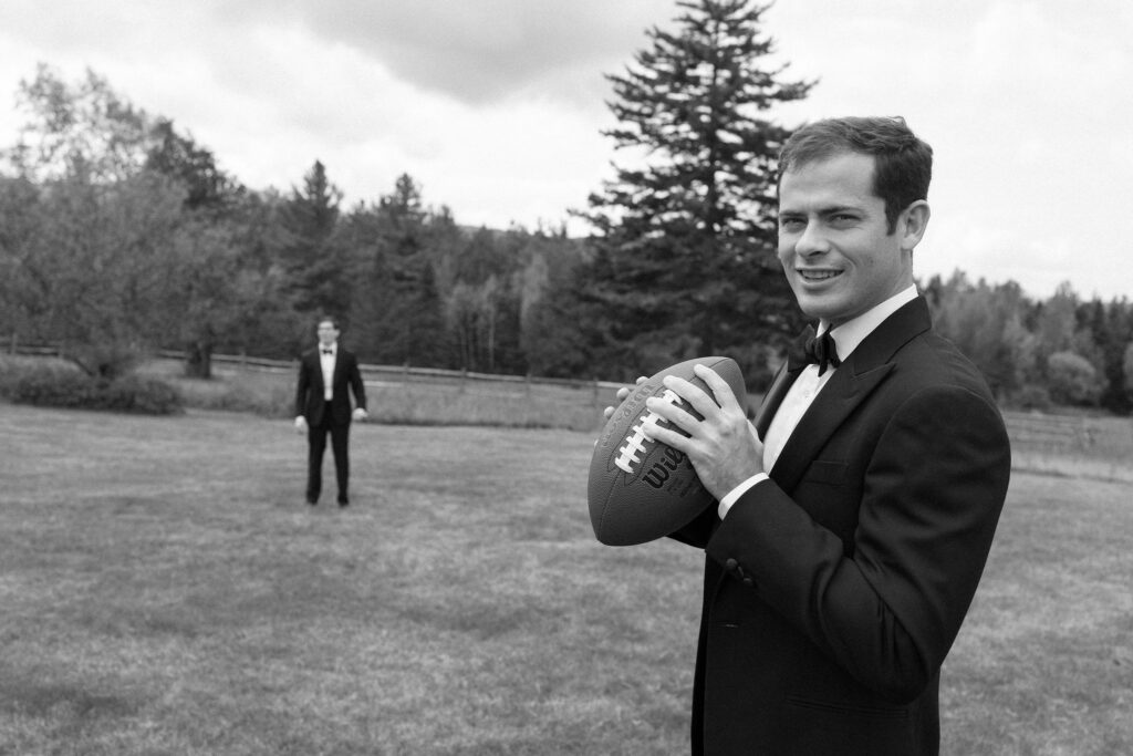 Groom tossing football with groomsman outside at River Ranch Lake Placid before wedding