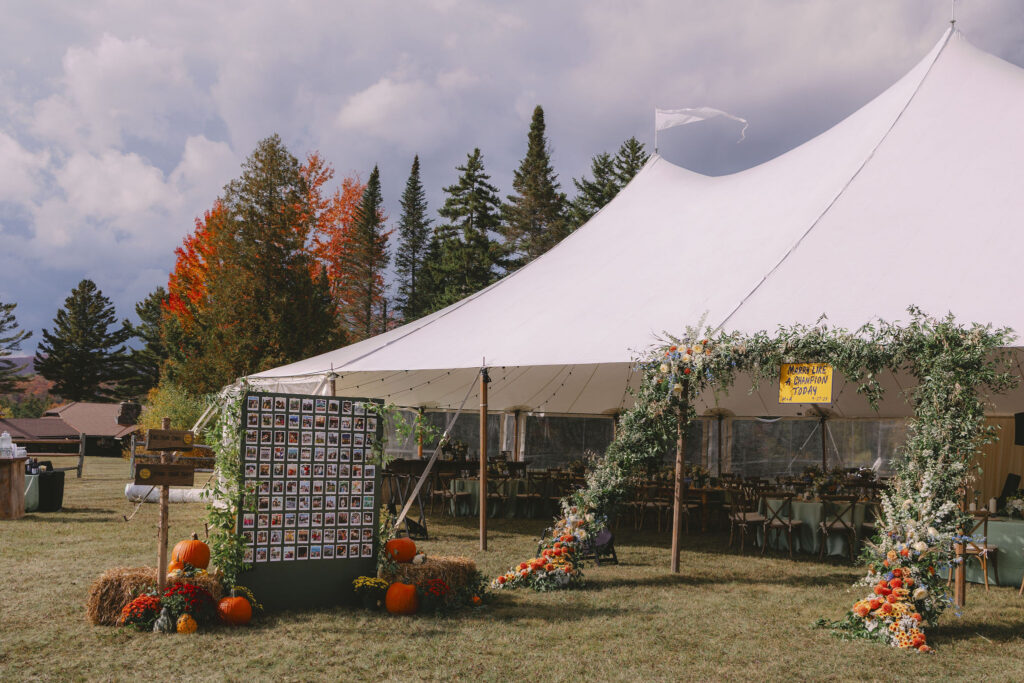 Sailcloth wedding tent decorated with greenery, florals, and pumpkins at a fall wedding in Lake Placid, New York.