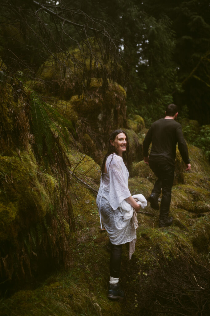 A bride looks over her shoulder as she and groom hike out of Sahalie Falls.